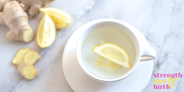 Ginger lemon tea in a white mug on a marble counter. An excellent tea for morning sickness and first trimester drinks.