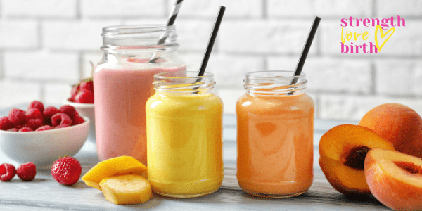 A set of three glass jar with straws and colorful fruit smoothies contained within. A lovely pink berry smoothie, a yellow mango smoothie and an orange papaya smoothie. Protein fruit smoothies are excellent for first trimester drinks. 